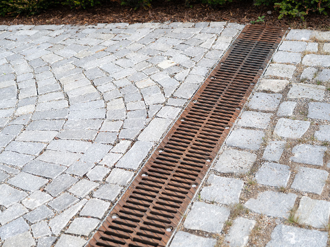Pflastersteinweg mit integriertem Ablaufgitter für Entwässerung.