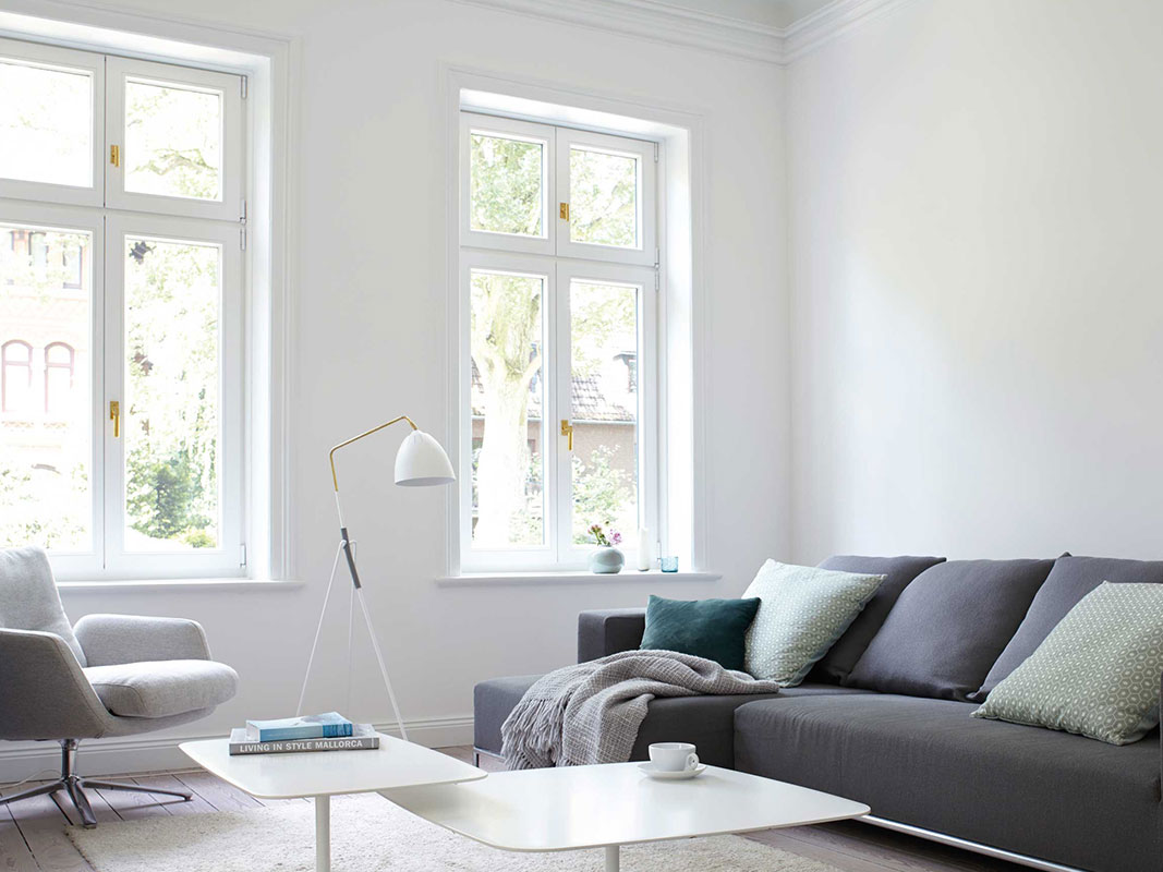 Helles Wohnzimmer mit grauem Sofa und weißer Stehlampe.
