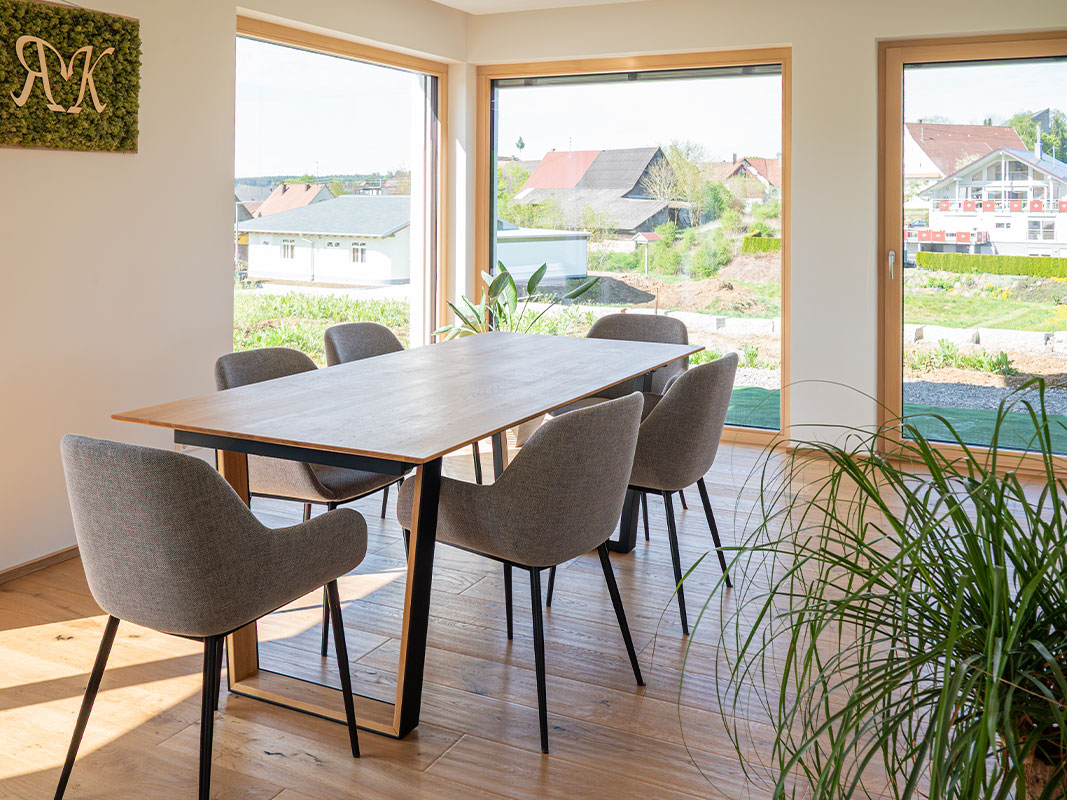 Essbereich mit sechs Stühlen um einen Tisch, drei große Fenster mit Blick in den Garten